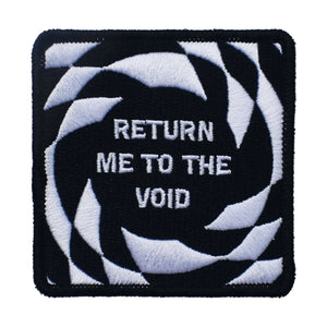 A square embroidered patch with a black border and black & white op art background. In the middle there is a black circle with “Return me to the void” written in white