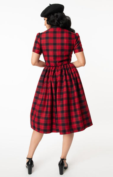 Cora Dress in rich red & black plaid features front button closure, fit & flare silhouette with gathered skirt in a just below the knee length, short puff shoulder sleeves, side seam pockets, and a black tie-closure collar. Shown back view on model.