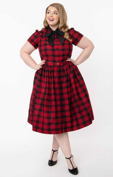 Cora Dress in rich red & black plaid features front button closure, fit & flare silhouette with gathered skirt in a just below the knee length, short puff shoulder sleeves, side seam pockets, and a black tie-closure collar. Shown on model.