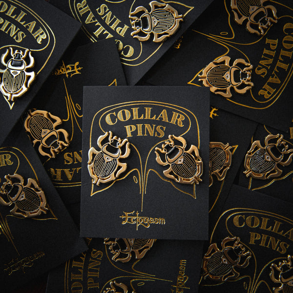 The pin set on its gold and black cardstock packaging 