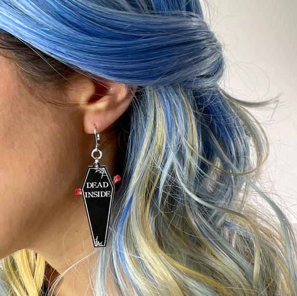 Two-tone black and white laser cut acrylic "Dead Inside" coffin dangle earring designed to swing open and reveal a skeleton-filled red interior bottom layer, shown on model