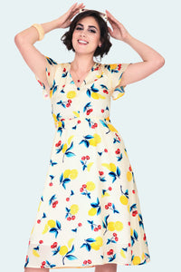 yellow background cherry lemonade print dress with v-neckline, covered button detail on the fitted bodice, short flutter sleeves, self belt, comfortable elasticized front waist seam, and flared below the knee length, shown on model