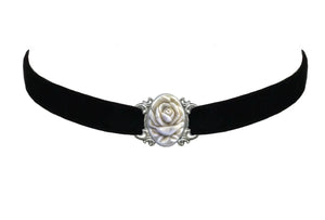 A black velvet choker necklace with a 1” x 1 1/4” detailed metal & carved plastic rose charm in an ivory color