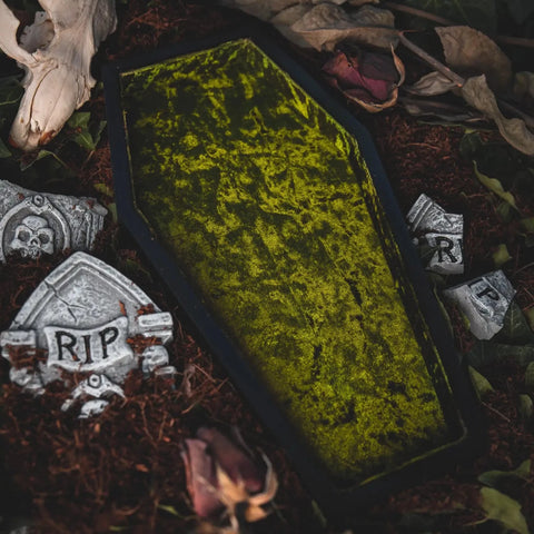 A shallow tray in the shape of a coffin lined with acid green crushed velvet