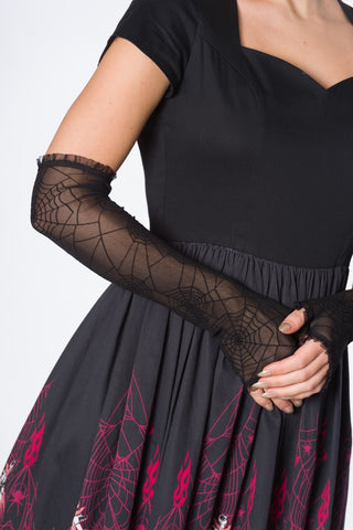 A model wearing a pair of mesh elbow length fingerless gloves with flocked spiderweb print and a ruffled trim