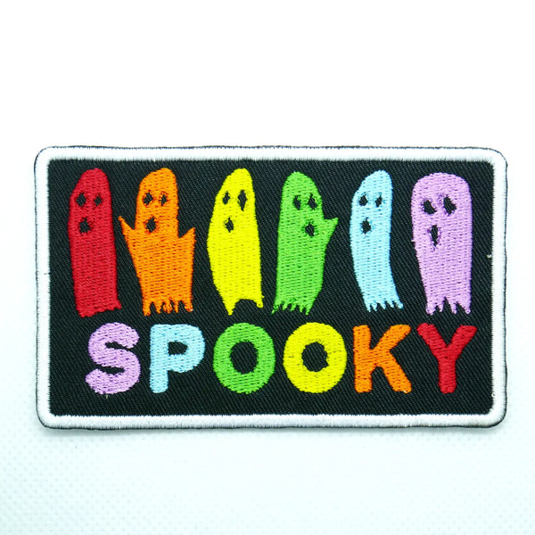 Rectangular patch with white border on a black background showing a row of ghosts in rainbow colors above the word “SPOOKY” also in rainbow lettering