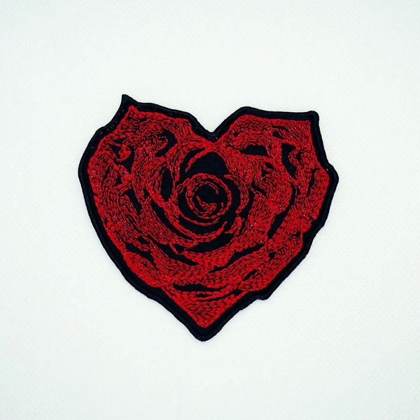 An intricate red rose embroidered patch in the shape of a heart on a black background