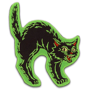 An embroidered patch of a vintage Halloween style black cat hissing with its back arched, with bright green details and border
