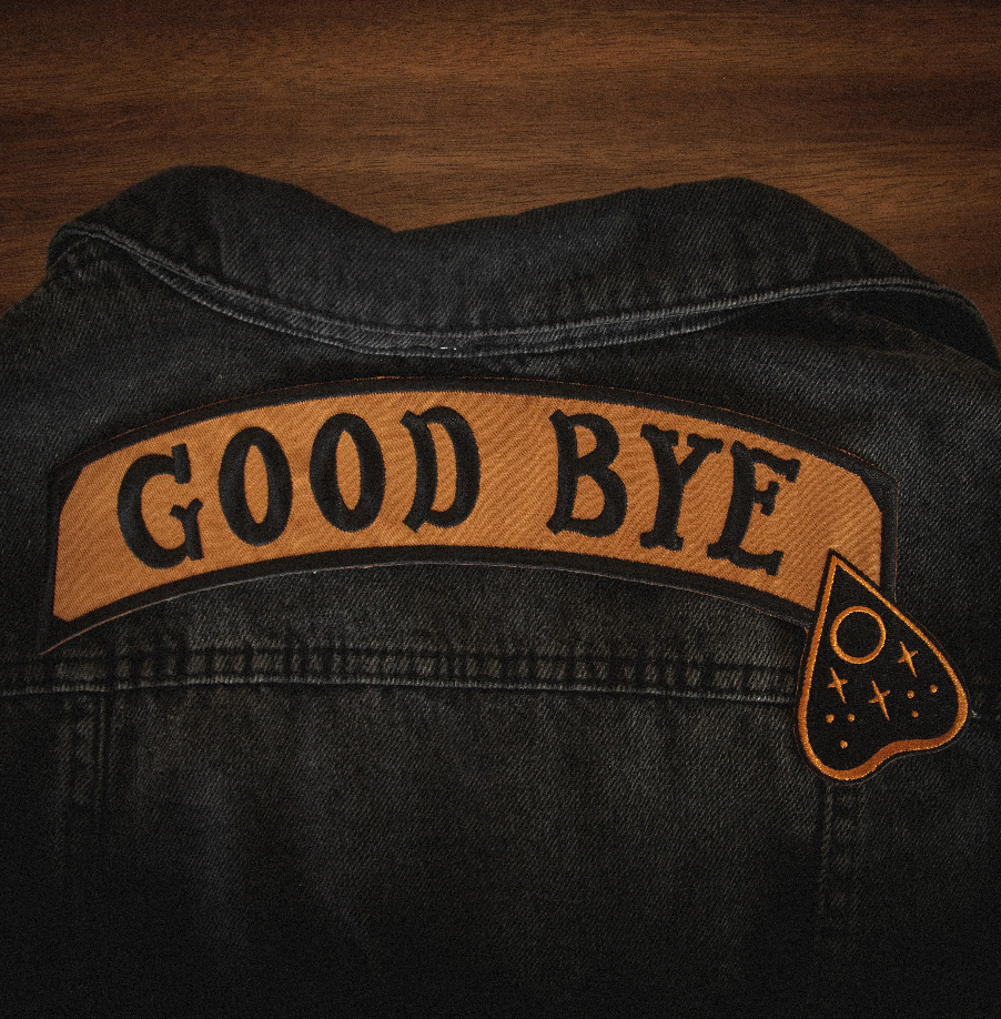 "GOOD BYE" message black stitching on light brown canvas banner with black Ouija board planchette embroidered back patch