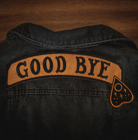 "GOOD BYE" message black stitching on light brown canvas banner with black Ouija board planchette embroidered back patch