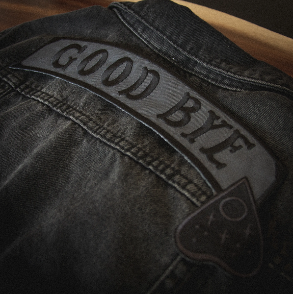 "GOOD BYE" message black stitching on dark grey canvas banner with black Ouija board planchette embroidered back patch