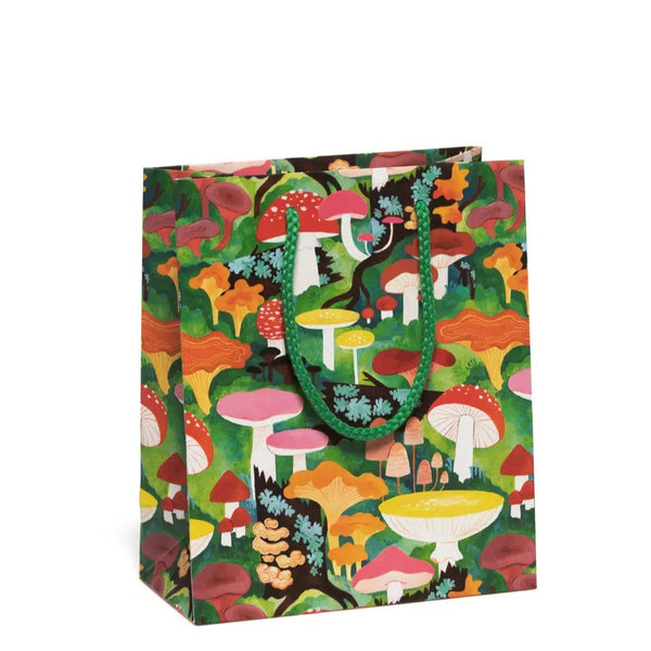 A gift bag with an allover print of beautiful multicolored mushrooms in a scenic nature background, illustrated by Kelsey Garrity Riley