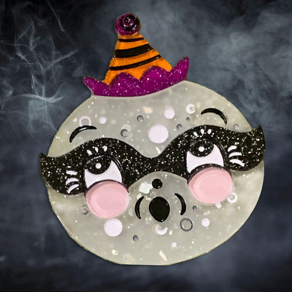 Luna Spooks full moon with pink cheeks wearing glitter black mask and purple and orange party hat layered laser cut resin brooch
