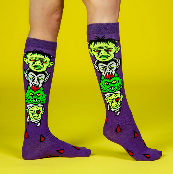 pair "Monster Mash" head stack of Mummy, Creature, Dracula, and Frankenstein's Monster on vibrant purple soft stretch cotton blend knee socks, shown on model