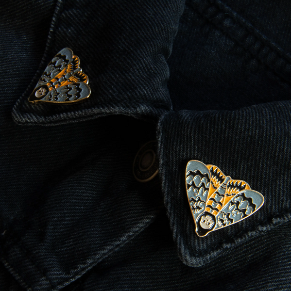 grey, golden yellow, and black enameled gold metal death's head moth clutch-back pin set to fit on collar points, shown on denim jacket