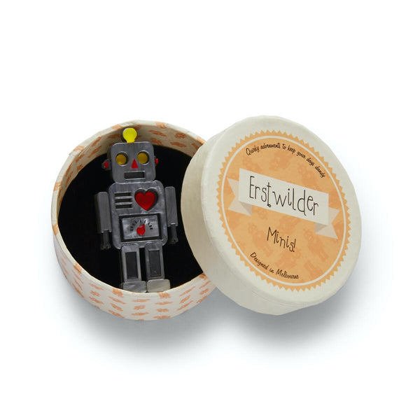 toy grey metal robot with red heart and yellow eyes 2 1/4" layered resin brooch, shown in illustrated Erstwilder round giftbox