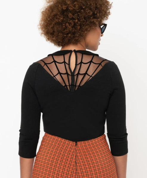 black stretch knit top with 3/4 sleeves, Peter Pan collar, front and back v-shaped spiderweb mesh neckline design, and removable jeweled spider brooch. shown back view on model