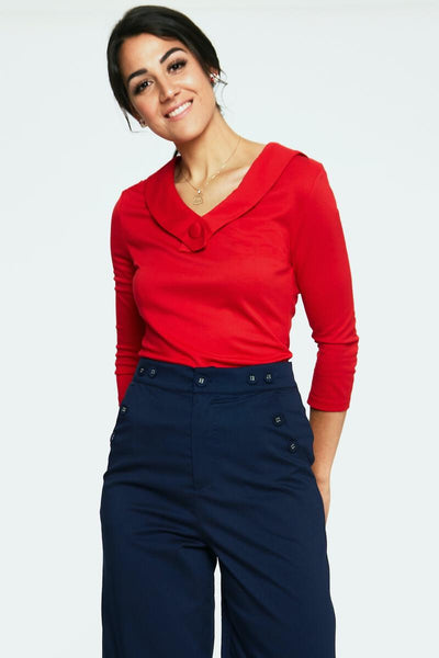 bright red stretch knit top with collared v-neckline with covered button detail, 3/4 length sleeves, fitted silhouette, and hip length. shown worn tucked in on model.