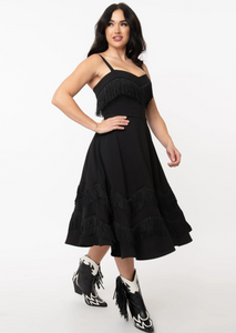 The Girlie Dress in black from Unique Vintage 3" black fringe princess-seamed structured bodice with sweetheart neckline, removable adjustable straps, and a full swing skirt in a below the knee length on model