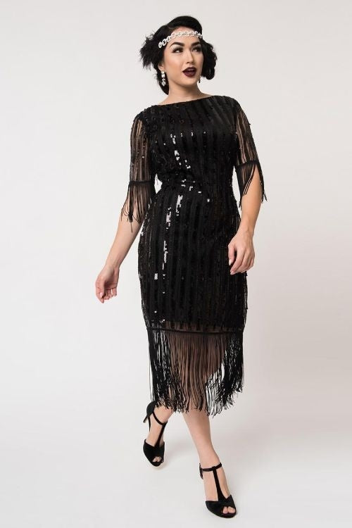 lined black mesh 1/2 sleeve Flapper dress adorned with vertical stripes of shiny black sequins and long fringe at the hem and sleeves, shown on model