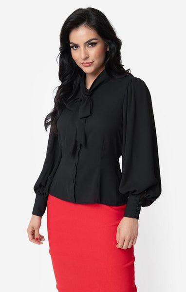 retro style Gwen Blouse in semi-sheer black crepe nipped in at the waist silhouette, full long sleeves with 3 1/2" button closure cuffs, and self-tie at the neck. Shown on model