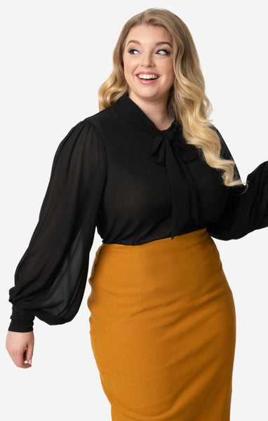 retro style Gwen Blouse in semi-sheer black crepe nipped in at the waist silhouette, full long sleeves with 3 1/2" button closure cuffs, and self-tie at the neck. Shown on model wearing it tucked into high waist skirt