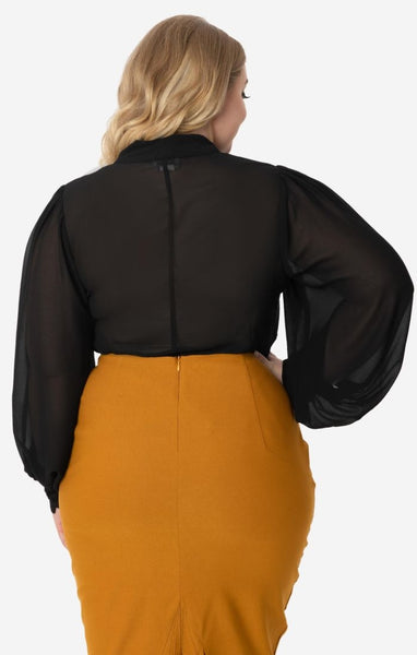 retro style Gwen Blouse in semi-sheer black crepe nipped in at the waist silhouette, full long sleeves with 3 1/2" button closure cuffs, and self-tie at the neck. Shown on model wearing it tucked into high waist skirt