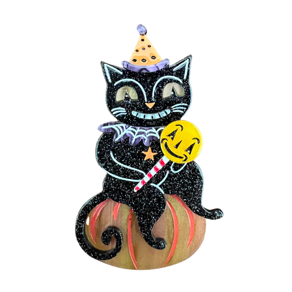 "Lollygagger" sassy smiling glitter black cat in a polka dot hat holding a yellow lollipop while perched on a pumpkin layered laser cut resin brooch