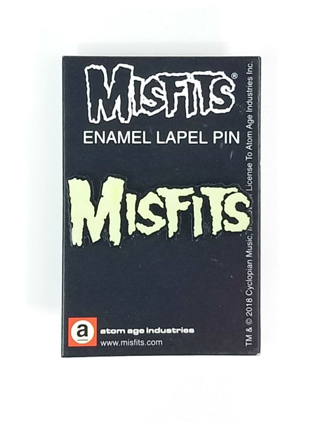"The Misfits" script logo glow-in-the-dark black enameled metal clutch back lapel pin, shown on illustrated backer card packaging