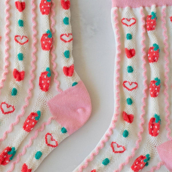 cotton knit socks in cream and pink with a textured knit-in pattern of red strawberries and hearts in alternating vertical stripes, showing close up detail