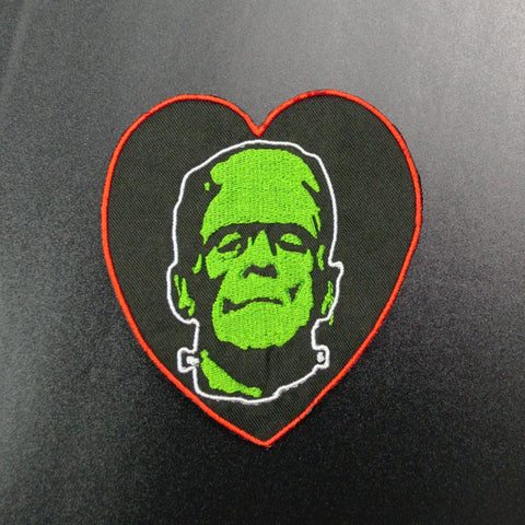 Frankenstein's monster face in green on a red bordered heart-shaped black canvas embroidered patch