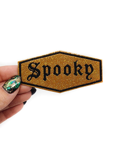 Black stitched border and Old English font "Spooky" text on sparkly deep gold glitter vinyl patch