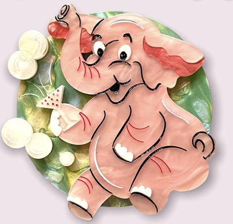 layered resin brooch depicting the classic alcohol-induced vision pink elephant, here holding a cocktail glass and surrounded by bubbles against a pearly pastel green circle background