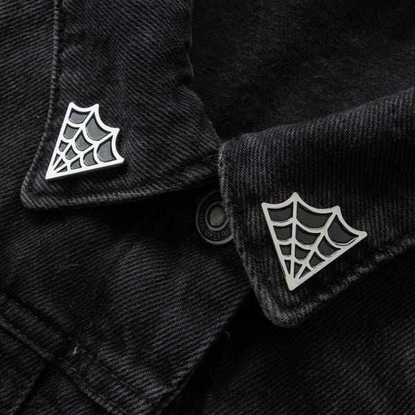 "Cobweb" black enameled silver metal clutch-back pin set to fit on collar points, shown on denim jacket