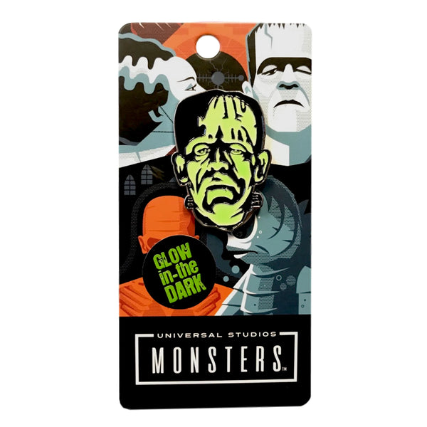 Glow-in-the-dark green enameled black metal pin depicting Boris Karloff in his iconic role as the monster from the classic 1931 movie, Frankenstein, shown on illustrated backer packaging