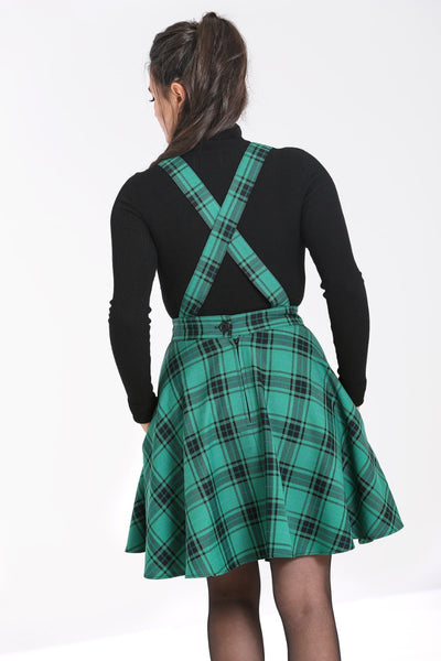 green and black plaid pinafore dress with crossover straps, front button closure, nipped in waist, and flared above the knee length skirt, styled with black turtleneck, shown on model