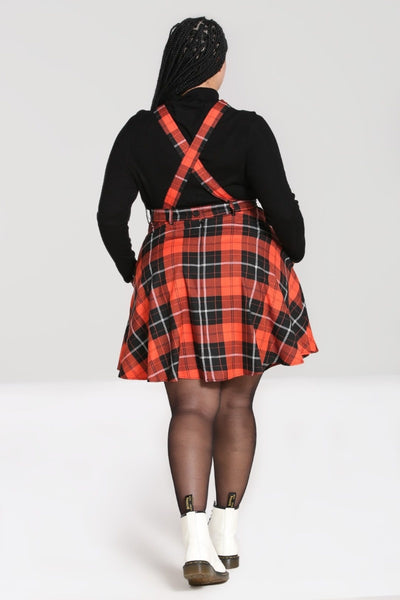 orange and black plaid pinafore dress with crossover straps, front button closure, nipped in waist, and flared above the knee length skirt, styled with black top, shown back view on model