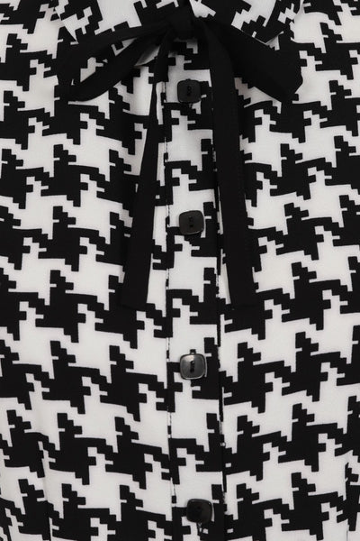 black and ivory houndstooth print short sleeve blose with black fabric tie at collar, showing cropped close up of collar, tie, and square black buttons