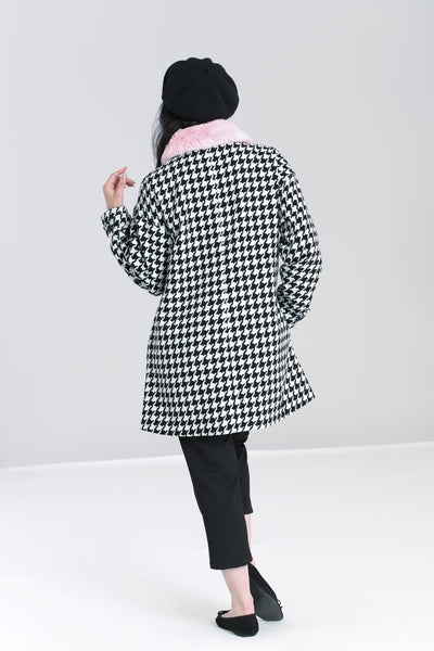 Black & white houndstooth long sleeve a-line coat with removable pink faux fur collar finished with a black velvet ribbon tie, shiny black buttons, and big patch pockets, shown on model