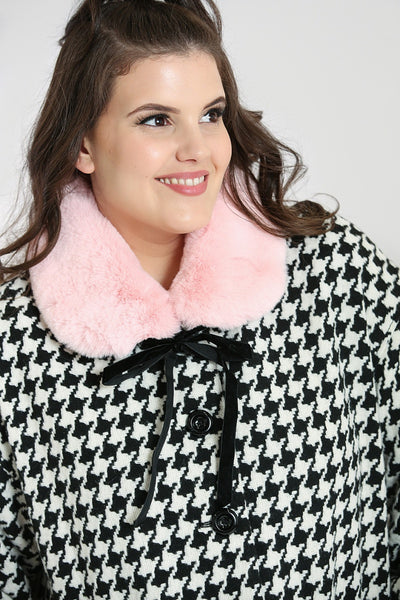 Black & white houndstooth long sleeve a-line coat with removable pink faux fur collar finished with a black velvet ribbon tie, shiny black buttons, and big patch pockets, shown on model
