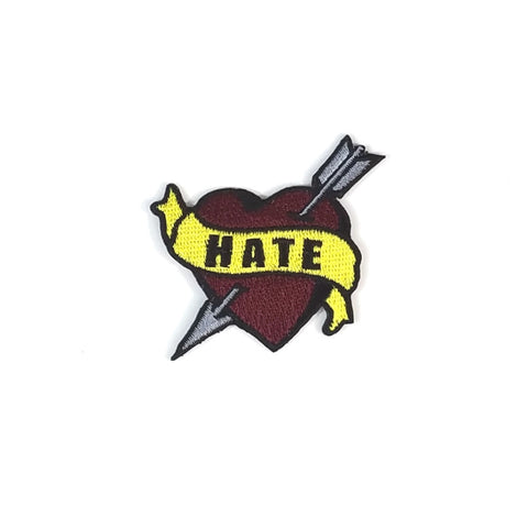 "Hate" black text on yellow banner scrolled across deep red grey arrow pierced tattoo flash heart