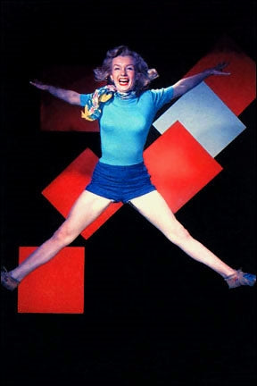 Marilyn Monroe in blue shorts and sweater photographed mid-air while jumping in front of red squares on black backdrop