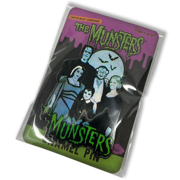 "The Munsters Family" enameled metal 1 5/8" x 2 1/4" clutch back pin, featuring the cast of the campy 60s TV show posing together in front of a full moon, shown on illustrated backer card packaging