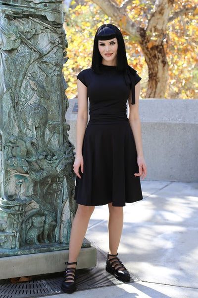 1940s inspired black stretch knit Bombshell Dress side tie at the neck, ruched waist, flared knee length skirt on model