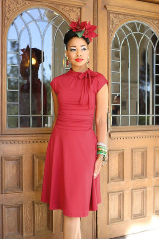 1940s inspired red stretch knit Bombshell Dress side tie at the neck, ruched waist, flared knee length skirt on model