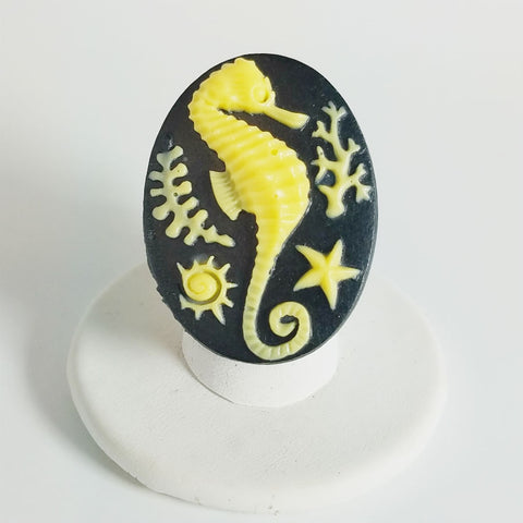 Cameo style buttery yellow seahorse in relief on a black oval with adjustable black glass bead stretch band ring