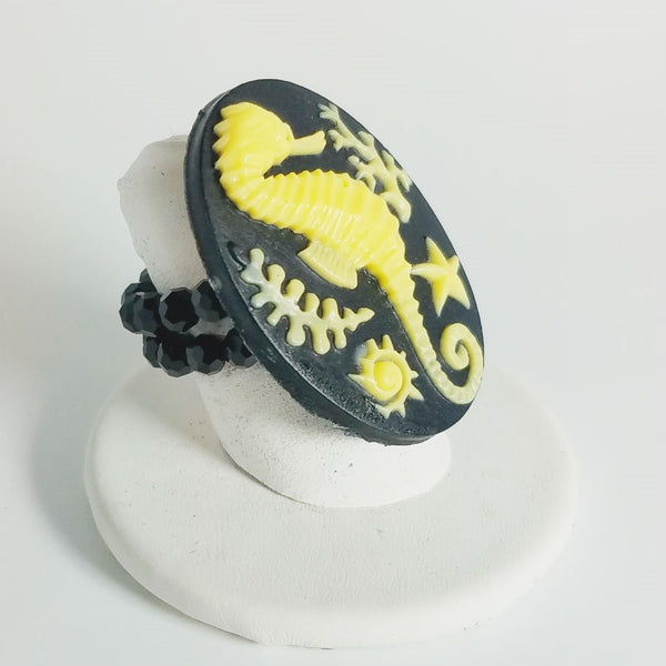 Cameo style buttery yellow seahorse in relief on a black oval with adjustable black glass bead stretch band ring
