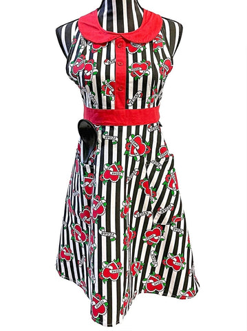full coverage bib front apron in black & white vertical stripe background "Vegan AF" print with two front patch pockets, red waistband and tieback closure, peter pan collar, and button placket detail, shown on striped dress form