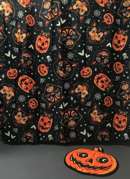 24" x 24" 100% polyester flannel orange and black grinning jack-o'-lantern shaped bath mat , shown displayed in bathroom with Halloween print shower curtain