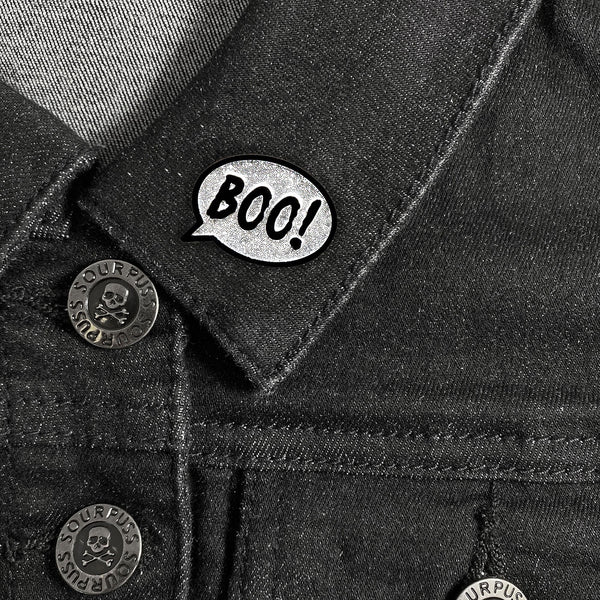"BOO!" speech balloon super glittery silver on black enameled metal clutch back pin, shown worn on collar of black denim jacket